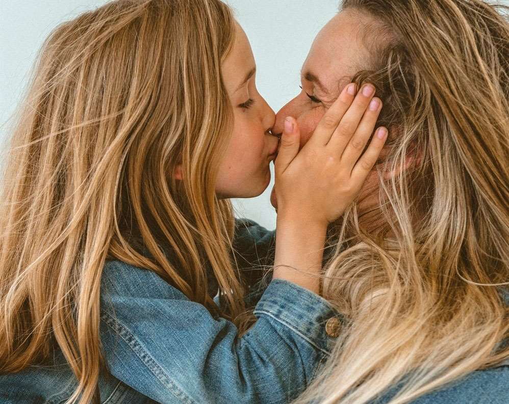 Barn kysser mor på et billede taget af professionel Børnefotograf